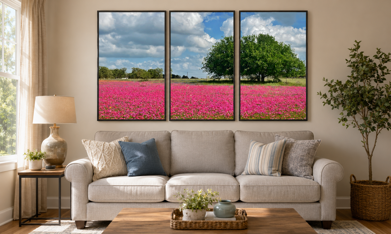 Three-panel triptych of a pink wildflower field hung above a sofa in a sunlit living room
