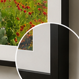 Close-up corner detail of a framed fine art paper print with a dark frame and mat